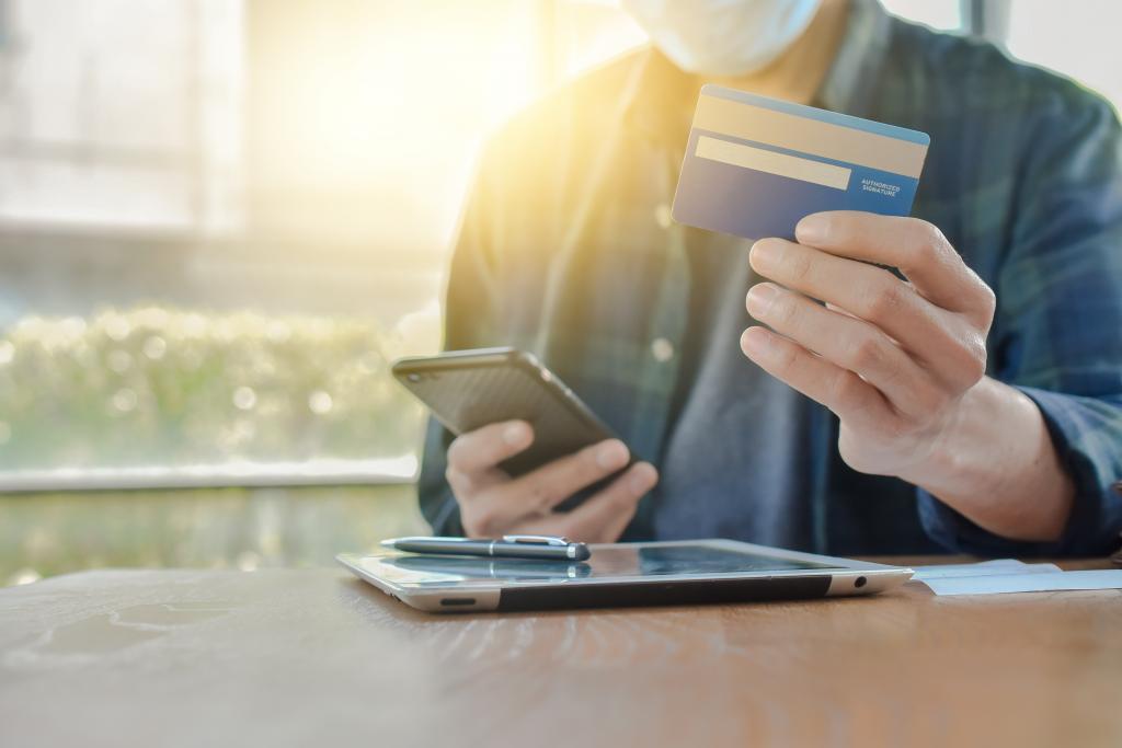 Hombre con un celular y una tarjeta de crédito en manos diferentes