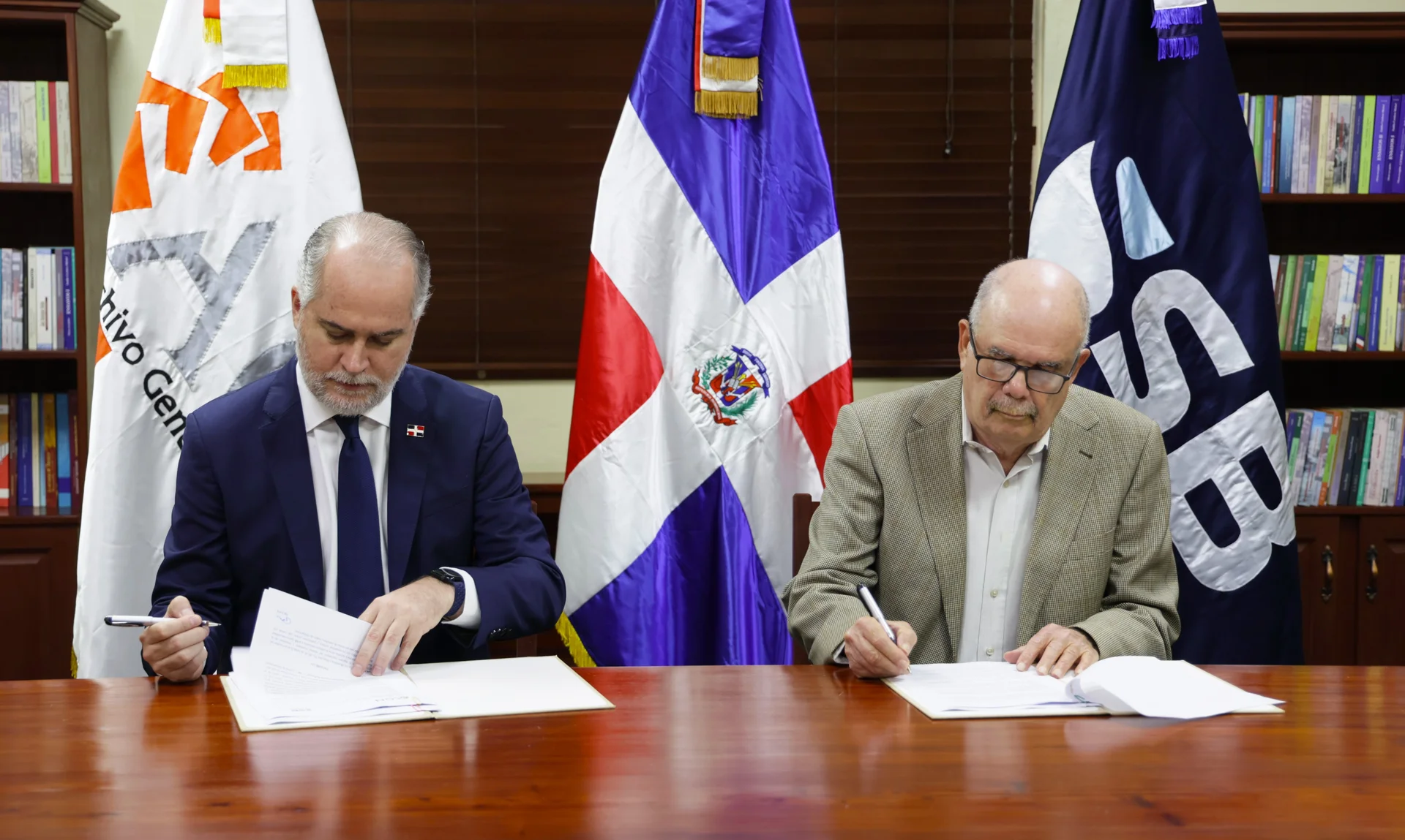 Superintendente de bancos junto a un funcionario público, firmando acuerdo